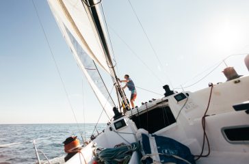 perfeccionamiento vela Deck of professional sailboat or racing yacht during competition on sunny and windy summer day, moving fast through waves and water, with spinnaker up, and ropes tied around winch