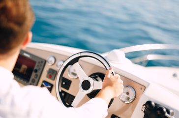 Man in a white shirt is driving a white motor boat. Close-up Man in a white shirt is driving a white motor boat. Close-up. High quality photo